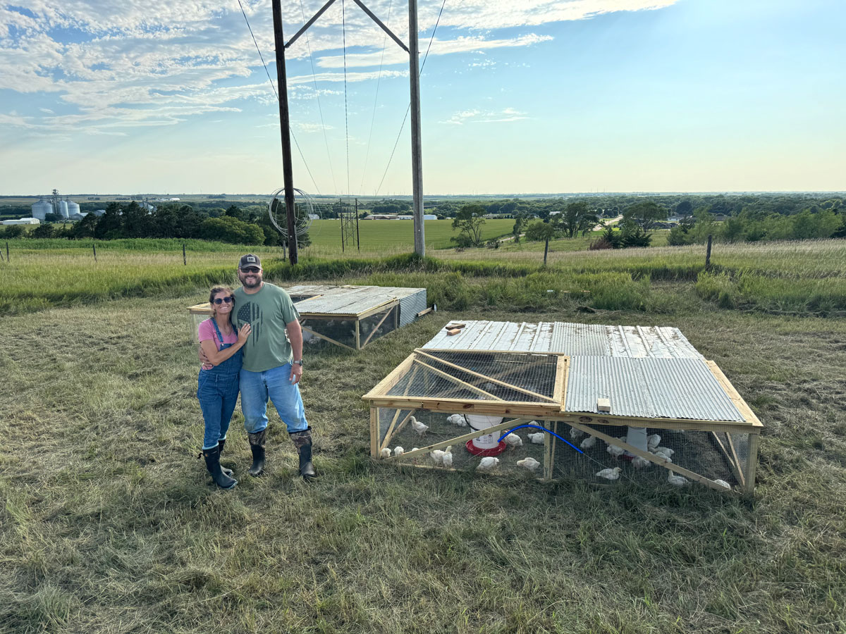 NE-Leigh Farm owners next to pastured poultry pens