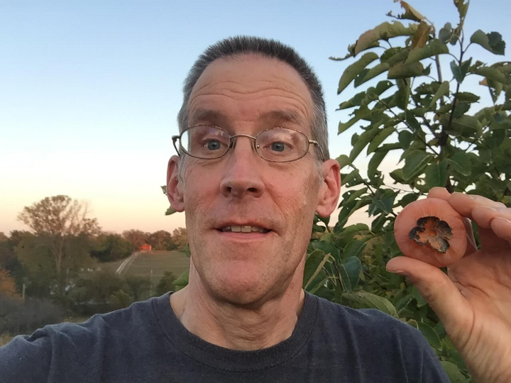 Daniel Kostka owner portrait holding a persimmon